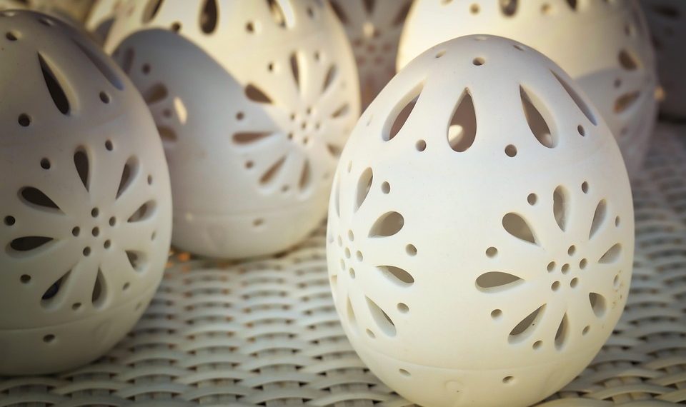 Decorative ceramic eggs with intricate cut-out patterns on display.
