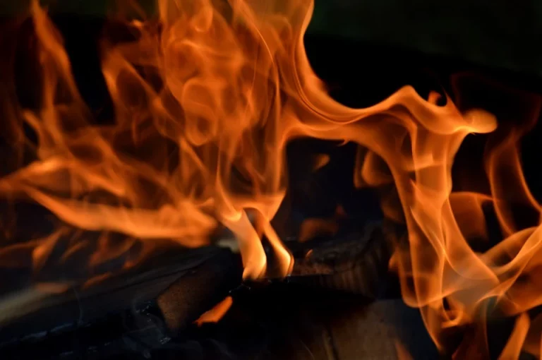 Fiery orange flames flicker intensely over burning wood.