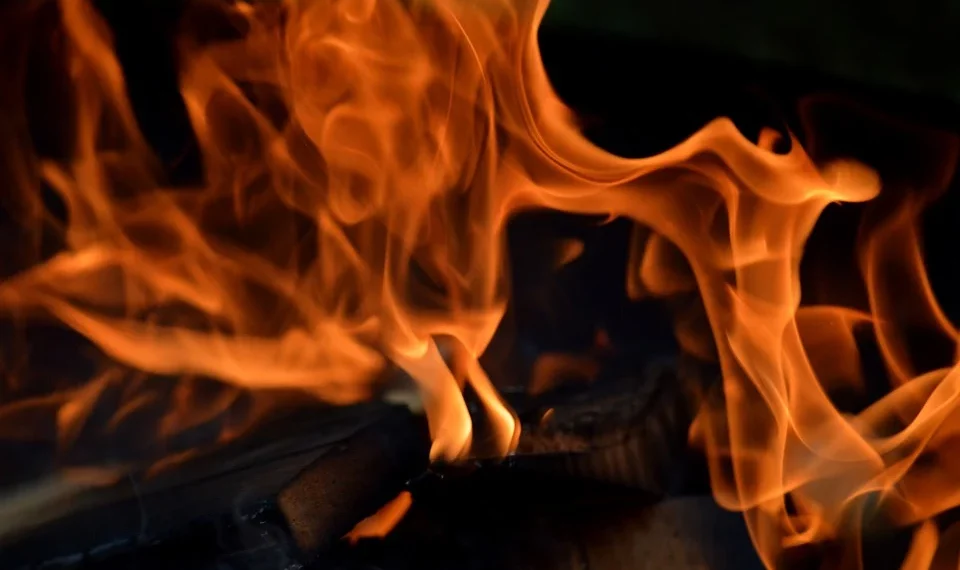 Fiery orange flames flicker intensely over burning wood.