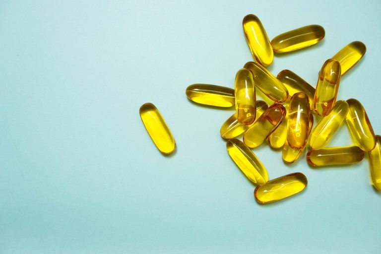Golden capsules scattered on a light blue background.