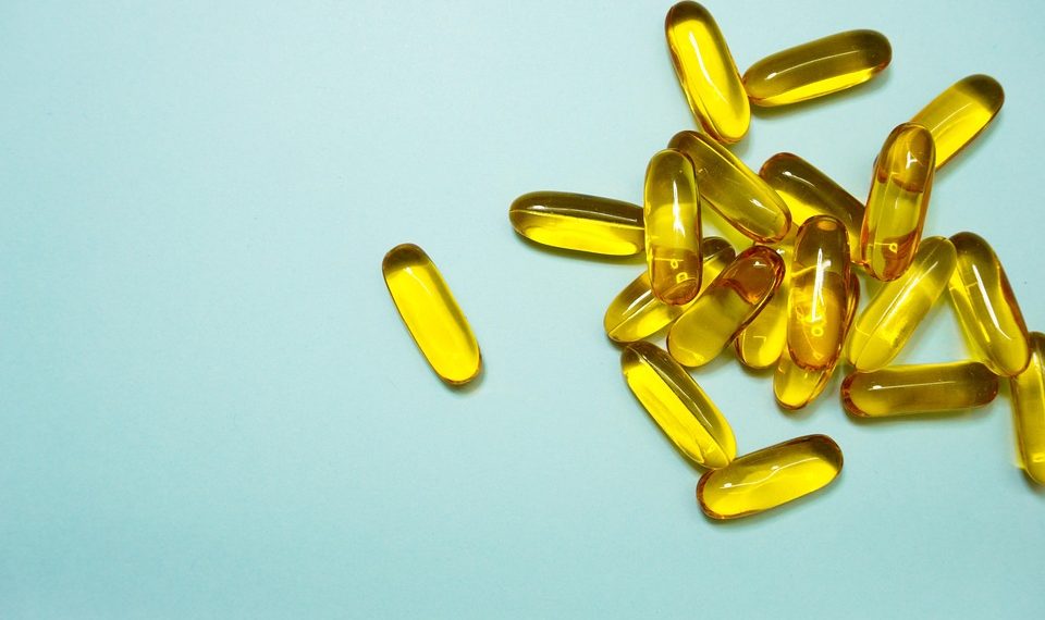 Golden capsules scattered on a light blue background.