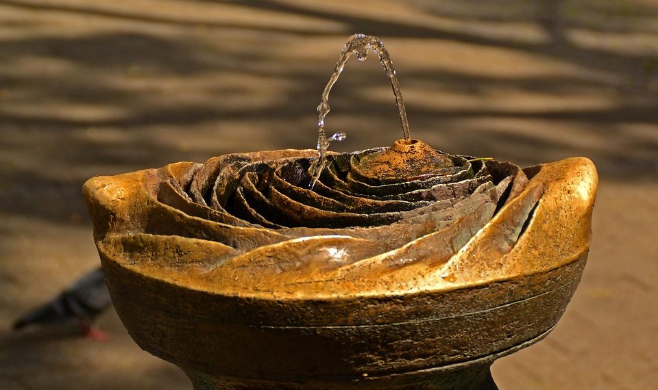Decorative stone garden fountain with flowing water.