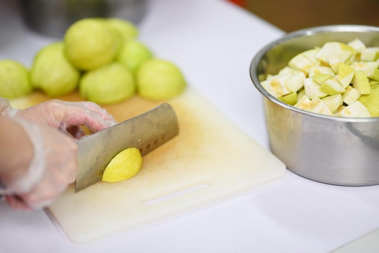 Chopping fresh guavas on a cutting board for a fruit salad.