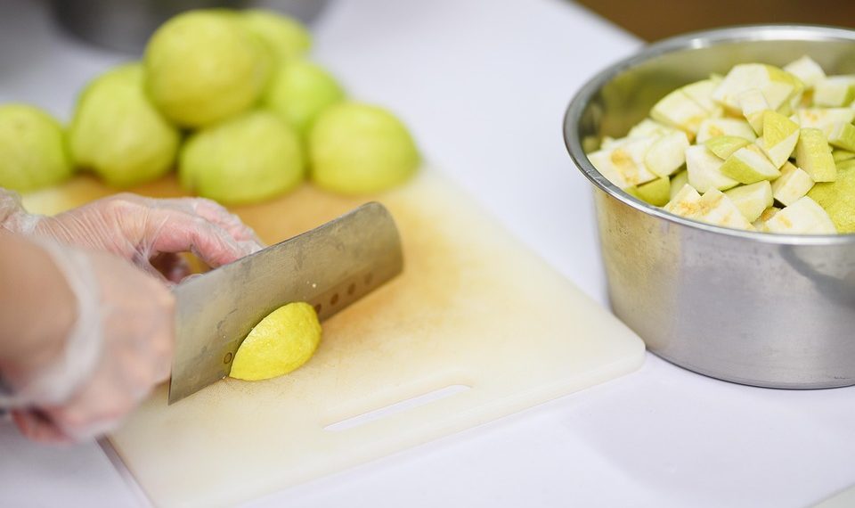 Chopping fresh guavas on a cutting board for a fruit salad.