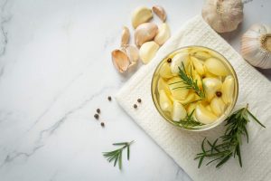 Garlic cloves with rosemary in a jar on a white cloth.