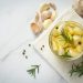Garlic cloves with rosemary in a jar on a white cloth.