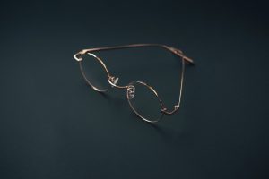 Round rose gold eyeglasses on a dark background.