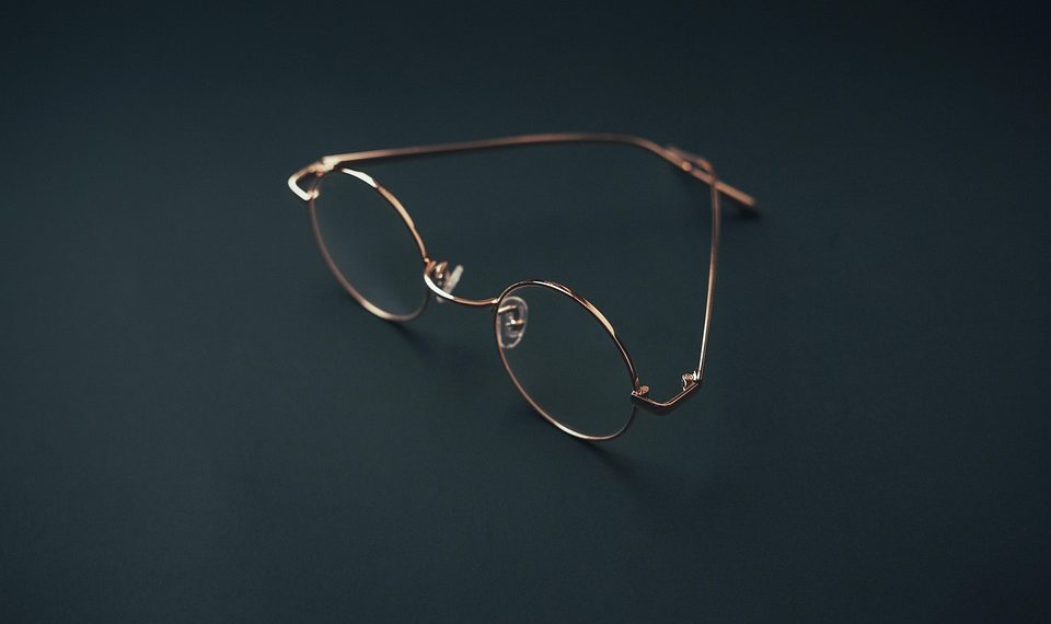Round rose gold eyeglasses on a dark background.