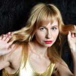 Blonde woman with red lipstick holding her long hair.