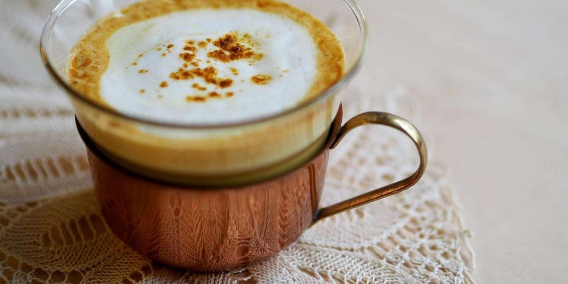 Creamy cappuccino in a glass cup on a lace doily.