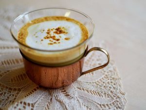 Creamy cappuccino in a glass cup on a lace doily.