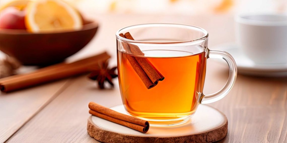 Warm spiced apple tea with cinnamon sticks on a table.