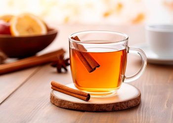 Warm spiced apple tea with cinnamon sticks on a table.