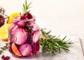 Pickled red onions in a jar with rosemary and lemon slices.