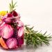 Pickled red onions in a jar with rosemary and lemon slices.
