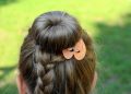 Braided hairstyle with decorative orange clip.