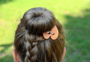 Braided hairstyle with decorative orange clip.