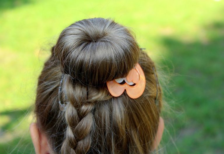 Braided hairstyle with decorative orange clip.