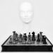 Chess pieces arranged on a board with a mannequin head in the background.