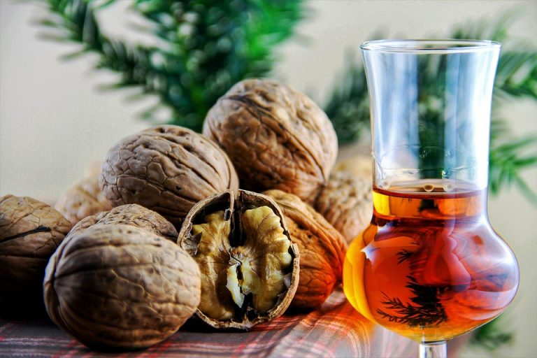 Walnuts and a glass of amber liquid on a table.