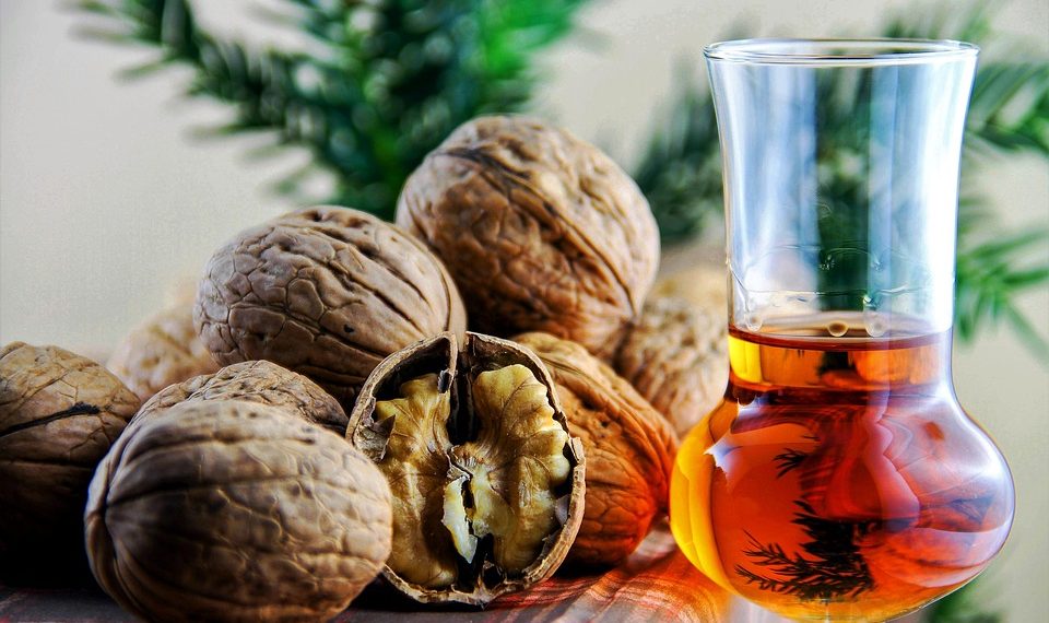 Walnuts and a glass of amber liquid on a table.