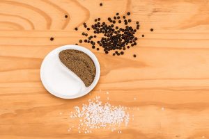 Salt and pepper in yin-yang shape on wooden table.