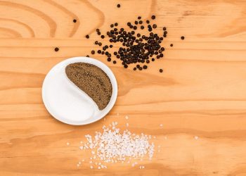 Salt and pepper in yin-yang shape on wooden table.