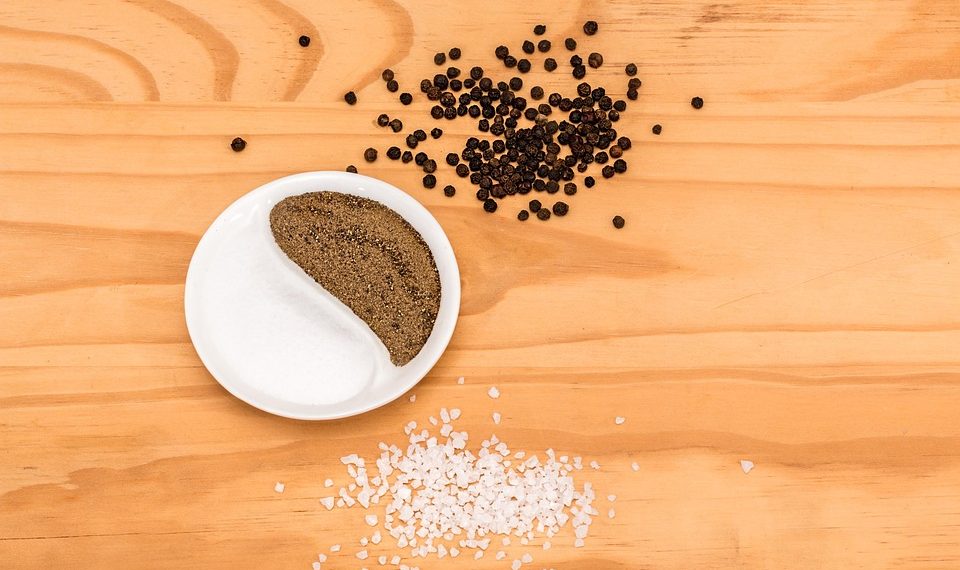 Salt and pepper in yin-yang shape on wooden table.