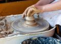 Hands shaping clay on a pottery wheel.