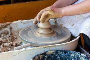 Hands shaping clay on a pottery wheel.