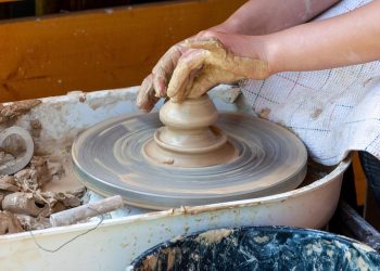 Hands shaping clay on a pottery wheel.