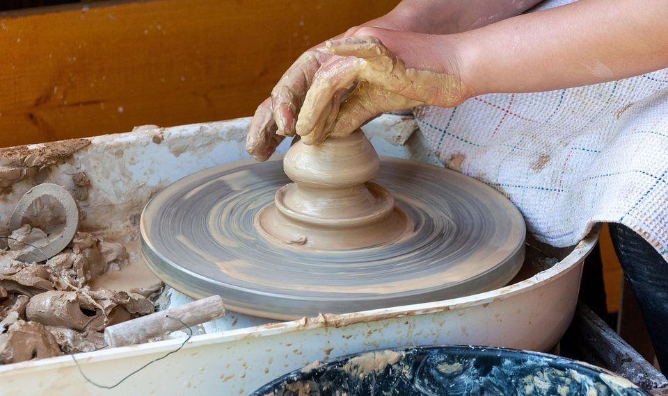 Hands shaping clay on a pottery wheel.