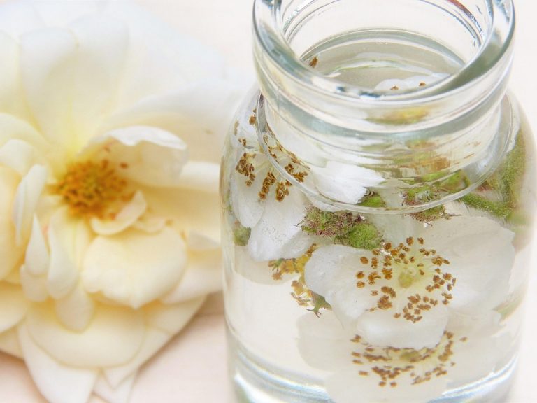 Jar of floral-infused water with rose petals.