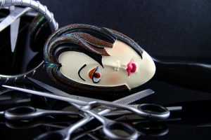 Comb featuring a stylized face with scissors on a reflective surface.