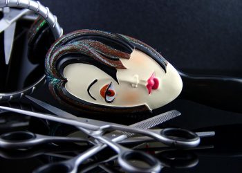 Comb featuring a stylized face with scissors on a reflective surface.