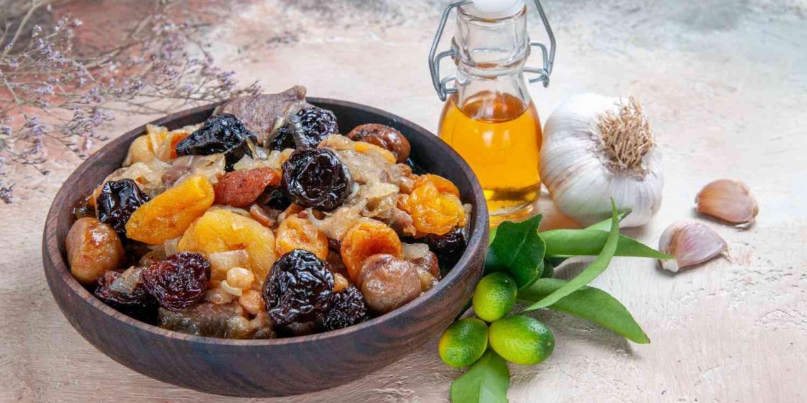 Roasted dried fruits and nuts in a wooden bowl, accompanied by garlic and olive oil.