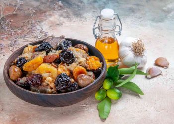Roasted dried fruits and nuts in a wooden bowl, accompanied by garlic and olive oil.