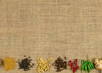 Spices and herbs arranged on burlap background.