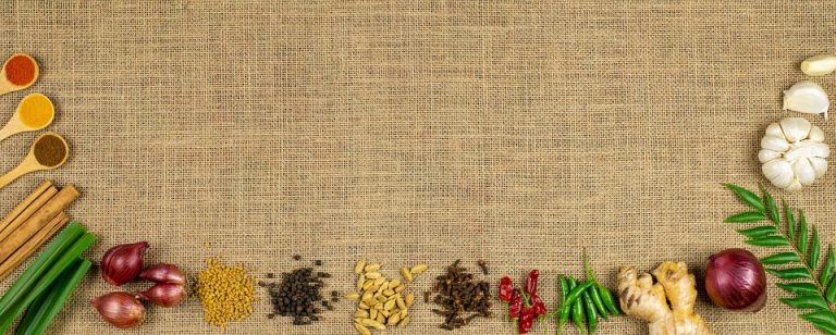 Spices and herbs arranged on burlap background.