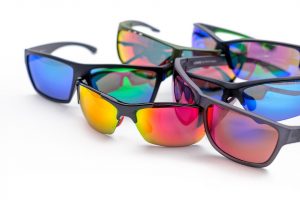 Colorful reflective sunglasses arranged on white surface.