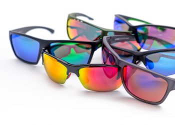 Colorful reflective sunglasses arranged on white surface.