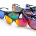 Colorful reflective sunglasses arranged on white surface.