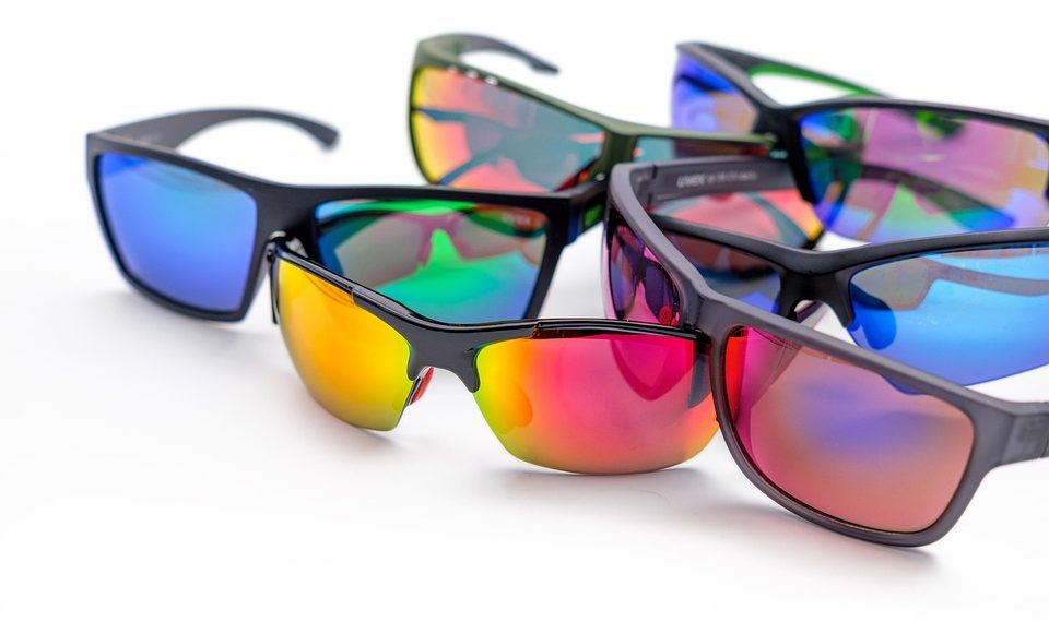 Colorful reflective sunglasses arranged on white surface.