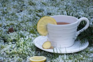 Warm ginger lemon tea cup in snowy garden setting.