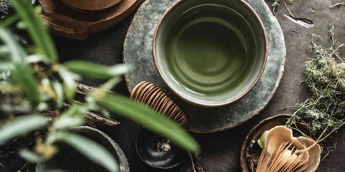 Green tea in a ceramic bowl surrounded by natural elements