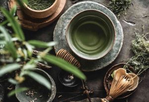 Green tea in a ceramic bowl surrounded by natural elements