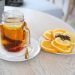 Hot tea in a glass mug with sliced oranges and cloves on a table.