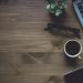 Laptop, coffee cup, glasses, plant on wooden desk.