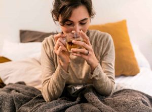 Woman enjoying a warm herbal tea in bed.