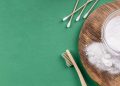 Baking soda on wooden board with bamboo toothbrush and cotton swabs.